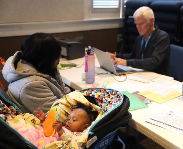 Diamond Williams waits with her 6-month-old daughter as volunteer Gates Moss prepares her return.