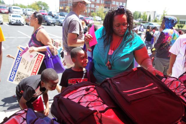 A mother and her children pick out backpacks at a Backpacks for Success distribution event.